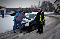 Dwie osoby odśnieżają samochód pod okiem policjanta drogówki