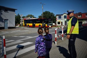 policjant przeprowadza dzieci przez przejście dla pieszych