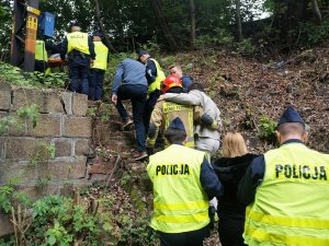 policjanci pomagają przy przeprowadzeniu osób poszkodowanych z miejsca wypadku, podtrzymują ich