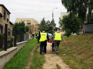 policjanci w kamizelkach odblaskowych niosą na noszach osobę poszkodowaną