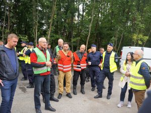 osoby w kamizelkach odblaskowych stoją i rozmawiają po zakończonych ćwiczeniach sztabowych