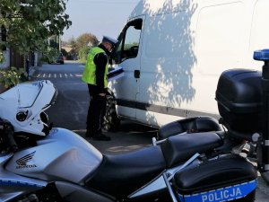 motocykl policyjny i policjant który przeprowadza kontrolę pojazdu, rozmawia z kierowcą zatrzymanego do kontroli busa