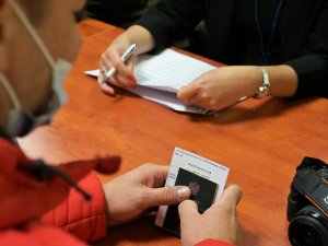 mężczyzna trzyma w rękach książeczkę wojskową, kobieta wypisuje dokumentację