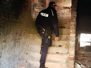 policjant wchodzi po schodach pustostanu, kontroluje czy przebywają tam osoby bezdomne