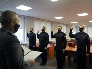 Policjanci stoją w szeregu przez Komendantem, mają uniesione dwa palce prawej ręki, wypowiadają rotę ślubowania przed Komendantem, który stoi naprzeciwko