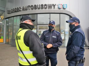 umundurowani policjanci rozmawiają z pracownikiem ochrony galerii handlowej, stoją przed wejściem do budynku Dworca Autobusowego