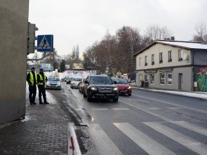 umundurowani funkcjonariusze wydziału ruchu drogowego stoją przy drodze i ruch pojazdów w rejonie skrzyżowania, auta dojeżdżają do skrzyżowania