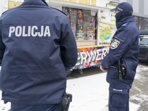 policjanci w mundurach stoją przed kioskiem z artykułami pirotechnicznymi