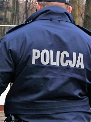 policjant w mundurze stoi tyłem, widać napis Policja znajdujący się na kurtce policyjnej