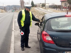 umundurowany policjant bada urządzeniem stan trzeźwości kierowcy zatrzymanego do kontroli  drogowej