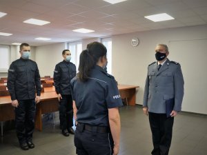 umundurowana policjantka składa raport Komendantowi Powiatowemu, z tyłu stoją na baczność nowi funkcjonariusze