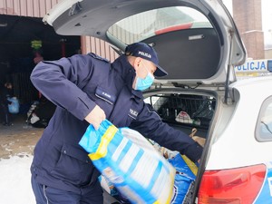 policjant wyjmuje z bagażnika radiowozu paczkę karmy dla zwierząt