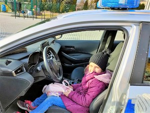dziewczynka siedzi na miejscu kierowcy w policyjnym radiowozie