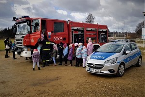 Zdjęcie przedstawia dzieci oglądające wóz strażacki i policyjny radiowóz.