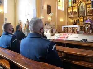 W kościelnych ławkach siedzi Komendant Powiatowy Policji w Wodzisławiu Śląskim i jego zastępca. Policjanci mają na sobie mundury galowe. W tle z ambony przemawia ksiądz.