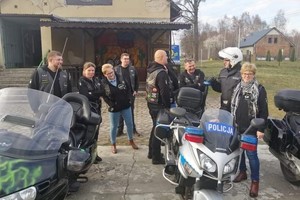 kobiety i mężczyźni stoją obok motocykla policyjnego i rozmawiają z policjantem w stroju motocyklowym