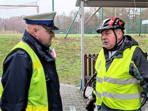 umundurowany policjant z drogówki rozmawia z mężczyzną w stroju na rower, który ma również na sobie kamizelkę odblaskową