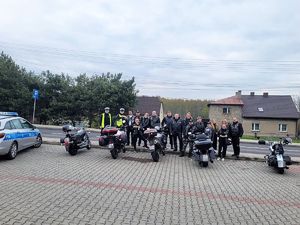 do wspólnego zdjęcia pozują motocykliści i dwaj umundurowani policjanci, obok grupy stoi zaparkowany radiowóz i motocykle