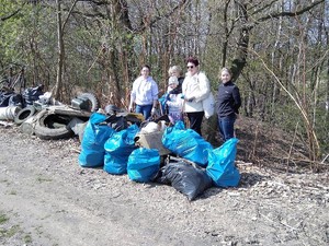 przy drodze leżą worki ze śmieciami, przed nimi stoi grupa osób, w tym dzieci. pozują do wspólnego zdjęcia po akcji sprzątania terenu gminy