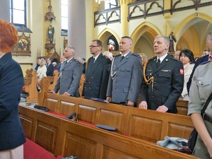 w kościelnej ławce stoją policjanci w mundurach galowych, obok nich stoi przedstawiciel Straży Miejskiej