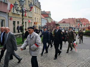 uroczysty przemarsz po rynku, wśród orszaku maszeruje Komendant Powiatowy w galowym mundurze