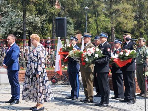 goście oraz przedstawiciele służb mundurowych składają przed pomnikiem kwiaty