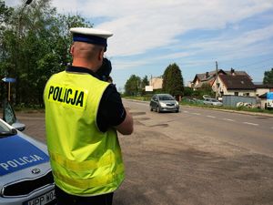 policjant specjalnym urządzeniem sprawdza prędkość przejeżdżających samochodów