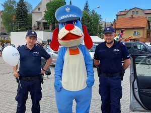 Dwaj policjanci pozują do zdjęcia z maskotką Śląskiej Policji, psem Sznupkiem