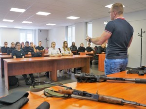 nieumundurowany policjant opowiada młodzieży siedzącej w ławkach o policyjnej pracy