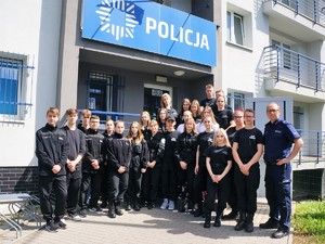 przed budynkiem komendy do wspólnego zdjęcia pozują uczniowie klas policyjnych i policjant