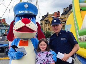 do wspólnego zdjęcia pozują policjant, maskotka śląskiej Policji, pies Sznupek i dziewczynka