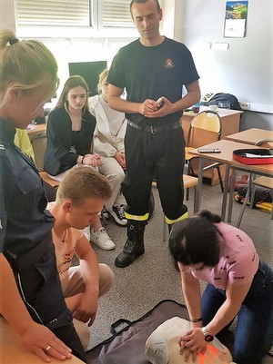 policjantka i strażak przyglądają się dziewczynie, która prowadzi resystutację na fantomie