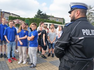policjant stoi przed grupą młodzieży