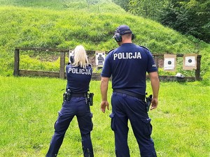 na strzelnicy, policjantka strzela do tarczy, obok niej stoi policjant, który obserwuje jej strzelanie