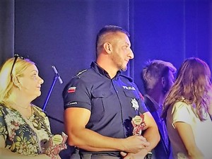 na scenie, obok innych wyróżnionych stoi umundurowany policjant