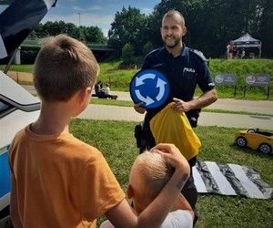 zdjęcie przedstawia policjanta, który pokazuje dzieciom znaki drogowe