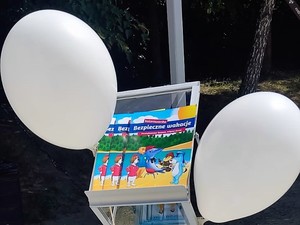na stojaku leżą ulotki dotyczące bezpiecznego wypoczynku, po obu stronach przyczepione są balony