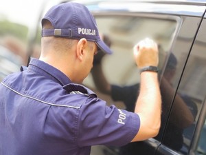 policjant stoi obok samochodu, zagląda do środka