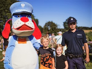 policjant i Sznupek pozują do zdjęcia z dziećmi