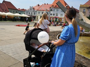 kobieta trzyma wózek, w którym leży niemowlę, kobieta do wózka ma przymocowany balon z nazwą wodzisławskiej policji