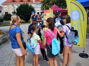 podczas festynu na rynku policjantka i policjant rozdają odblaskowe smycze uczestnikom festynu