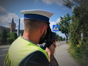 policjant kontroluje urządzeniem prędkość przejeżdżających pojazdów