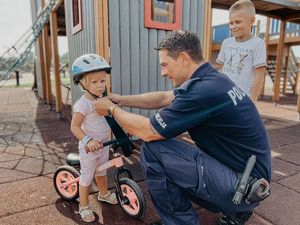 Policjant zakłada dziecku kask rowerowy na głowę