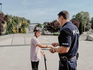 Policjant zakłada chłopcu z hulajnogą odblask na rękę