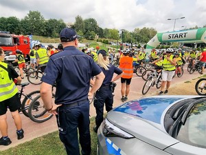 policjanci stoją przed uczestnikami rajdu rowerowego