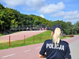 w parku policjantka przygląda się grupie rowerzystów, z kaskami na głowach, przygotowani do jazdy na pumptrucku