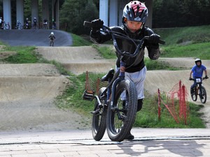 dziecko w kasku na głowie podjeżdża rowerem na pumptracku