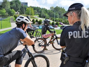 policjantka stoi obok grupy osób na rowerach podczas treningu na rowerowym torze zjazdowym