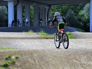 zawodnik w kasku na głowie zjeżdża na rowerze po pumptracku