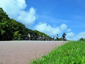 na rowerowym torze zjazdowym stoją przygotowani do zjazdu rowerzyści w kaskach na głowach